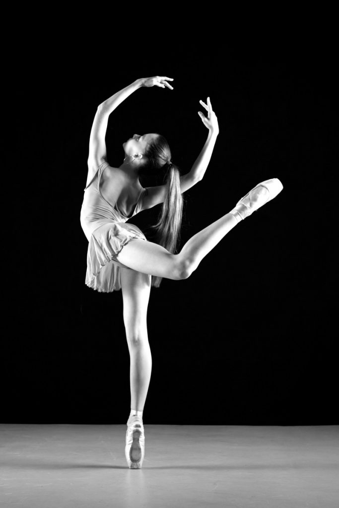 Baletttänzerin, auf dem rechten Bein im Spitzenstand eine Piruette drehend. Bild in schwarz weiß.
