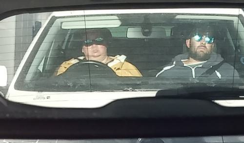 Zwei Menschen im Auto auf den vorderen Sitzen, durch einen Rückspiegel.