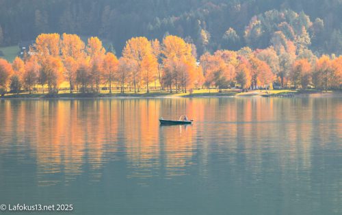 Idylle am Wolfgangsee, in der Mitte des Bildes ist ein Fischer mit seinem Boot 