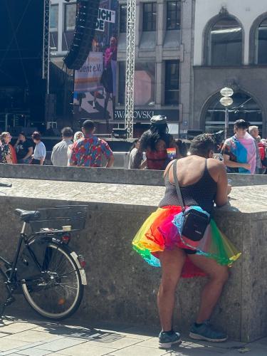 Ein Mann mit einem bunten Rock, aufgelehnt auf einer Mauer auf dem Christoffer Street Day. 