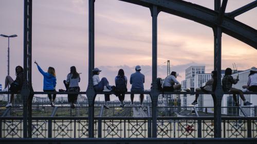 Menschen sitzen auf einer Stange auf der Hackerbrücke