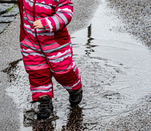 ein Kind versucht Wasser zu treten im Regen. 